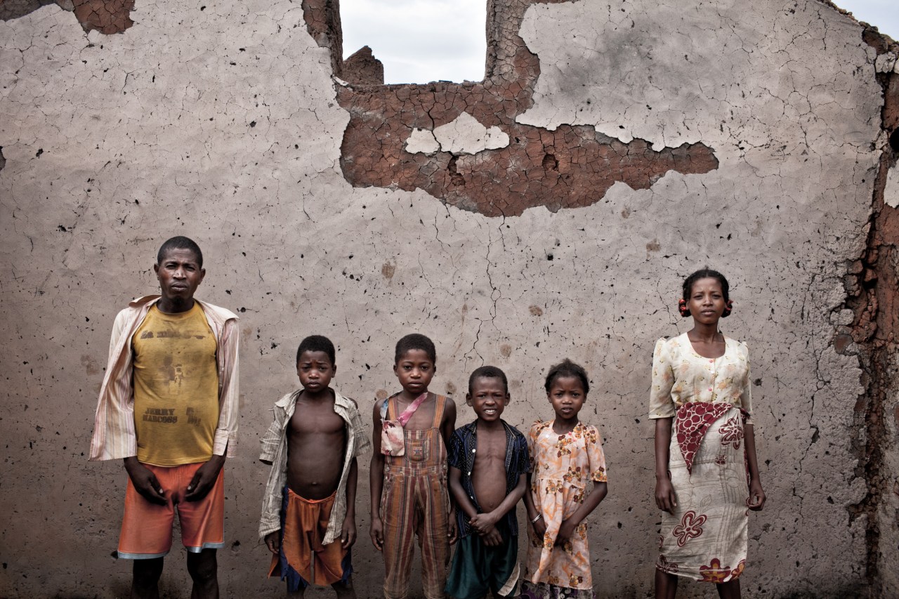 Jean-Baptiste poses with his wife and kids in their house’s ruins. “We were coming back from the rice fields when we saw the military men burning our house down. I remember it well, it was a Monday around noon. They took one of our zebus for them to eat."