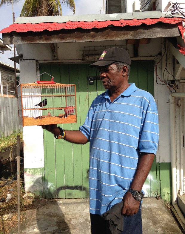 Cecil Bess poses with a bird in front of his house. (Photo by Phillip Pantuso)