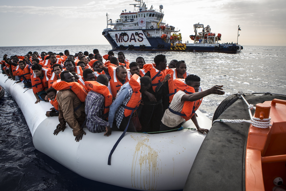 Migrants on a rubber boat transfer to a faster rescue craft.