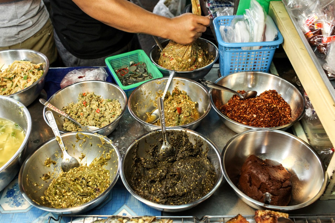 Five chili pastes at the market (clockwise from top center): nam prik sa mun pri (herb paste), nam prik kha (galangal paste), nam prik tha dang, and two versions of nam prik num.