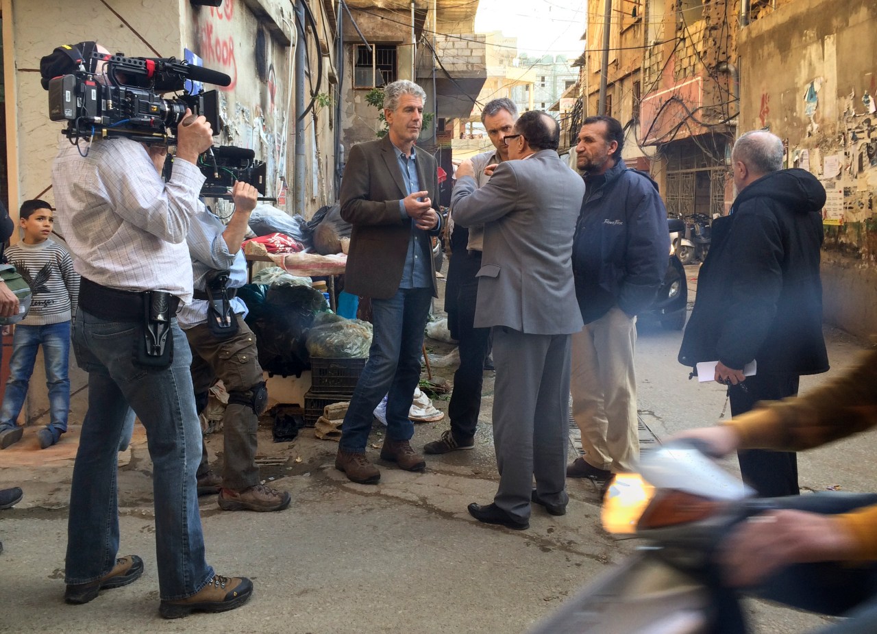 Bourdain and Nick Patton Walsh (to Bourdain's immediate left) speak with Mr. Najem (back to camera).