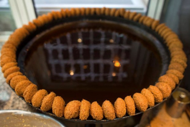 A ring of freshly fried falafel. The building across the street, reflected in the falafel oil, was gutted during the civil war and has never been rebuilt.