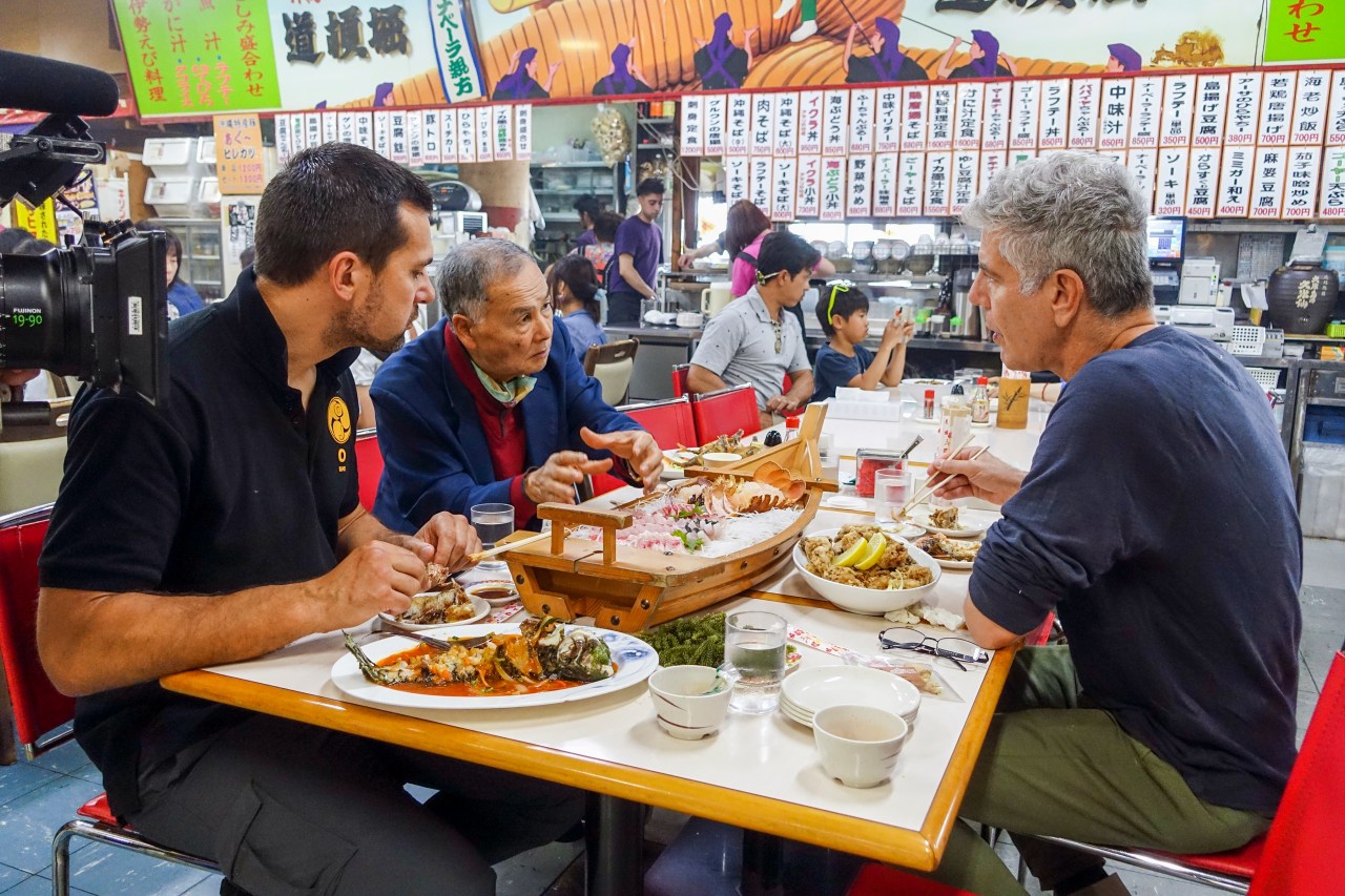 Bourdain eats with Master Hokama Tetsuhiro (middle) and black belt/translator James Pankiewicz (left) at Makishi Public Market in Naha, Okinawa.