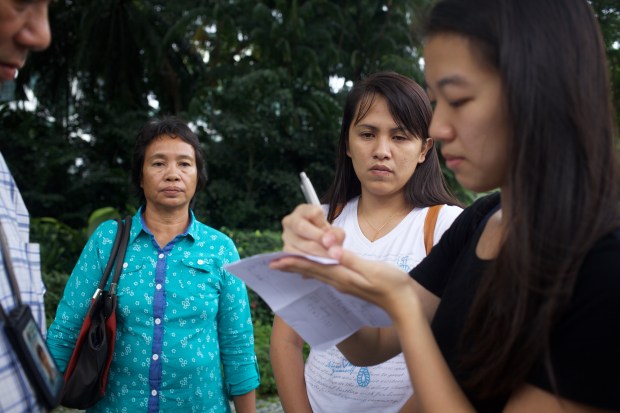 Jading's mother and sister looking on as an anti-death penalty activist writes down everyone's particulars for the security officer while submitting a personal letter of appeal to the President of Singapore to show mercy to Jabing.