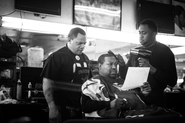 1. Reggie "Feeny" Ward Jr. reads a football poll to barbers Kevin Adams and Edward Azeem. Feeny was a regular customer until he passed away a few months ago. / 2. Joseph Cook waits for a ride outside of Dave's Barber Shop after getting his hair cut.