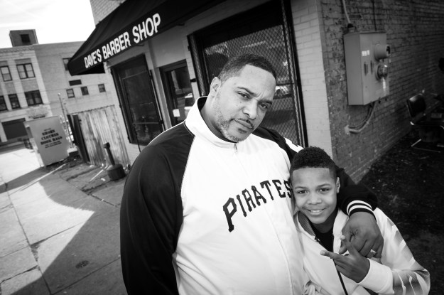 1. Richard Smith poses with his son Noah outside of Dave's Barber Shop after they both received fresh haircuts. Smith, a regular, has been bringing his son since his first haircut. / 2. Ericka Bibins smiles as her son tries to hide when the barber jokes about his upcoming haircut.