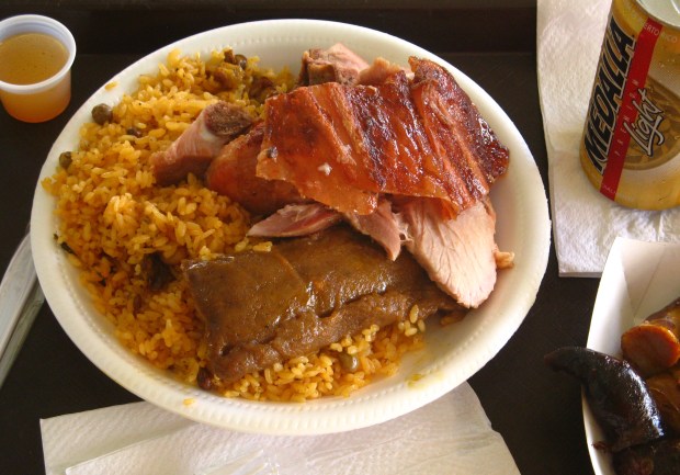 Lechon served with plantain tamal, rice, pork sausage, and blood sausage. (Photo by sfchef via flickr.com)