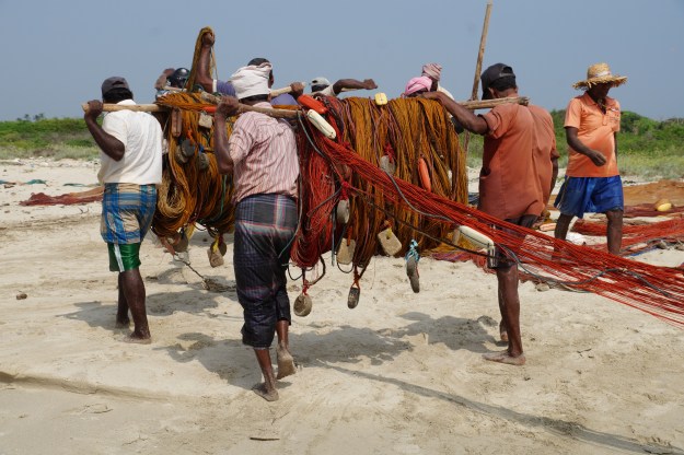 1. Carrying the karavalai equipment back to the truck after lunch. The team of fishermen will drive a bit farther down the coast and set up for a second round in the afternoon. 2. Pulling in the karavalai net after three hours waiting on the shore.