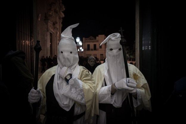 1. Two "Pappamusci" worshippers in a church during the Holy Week pilgrimage in Francavilla Fontana. Pairs of barefoot penitents dressed in white visit all of the churches in the city throughout the night to ask for forgiveness from the Lord. Their identity is kept strictly secret. / 2. In Noicattaro, Molfetta, Francavilla Fontana and other cities of Apulia, hooded penitents called “Cruciferi” drag crosses along the streets in procession.