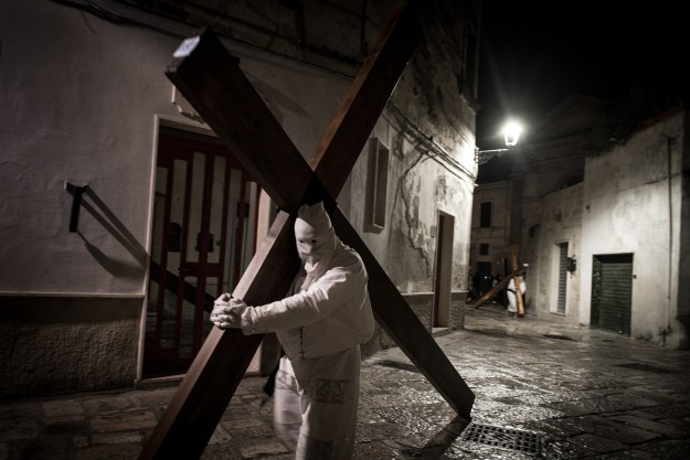 1. Two "Pappamusci" worshippers in a church during the Holy Week pilgrimage in Francavilla Fontana. Pairs of barefoot penitents dressed in white visit all of the churches in the city throughout the night to ask for forgiveness from the Lord. Their identity is kept strictly secret. / 2. In Noicattaro, Molfetta, Francavilla Fontana and other cities of Apulia, hooded penitents called “Cruciferi” drag crosses along the streets in procession.