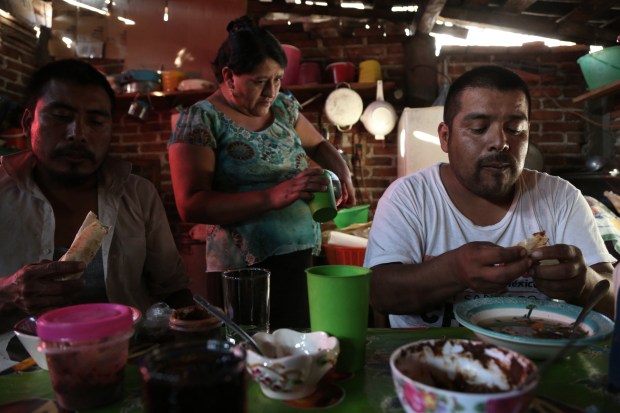 Fortunato Angeles and his brother-in-law, Raul Marin, eat pozole and fresh tortillas after a day at the palenque in San Juan del Rio, Oaxaca.