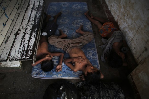 1. Children nap during the day’s heat on a mattress between the station’s wooden benches. / 2. A mother bathes her son at the station. One of the benefits of living at the station is running water.