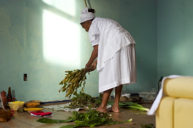 Photo 1: Plants with names such as “path opener,” “battle winner” and “knock it all down” are sprinkled with pemba, roots and herbs that are  finely ground and correspond to the Orisha for which they are destined. Photo 2: Mãe Marta gathers plants to cleanse the physical, and spiritual energy of the house and its residents.