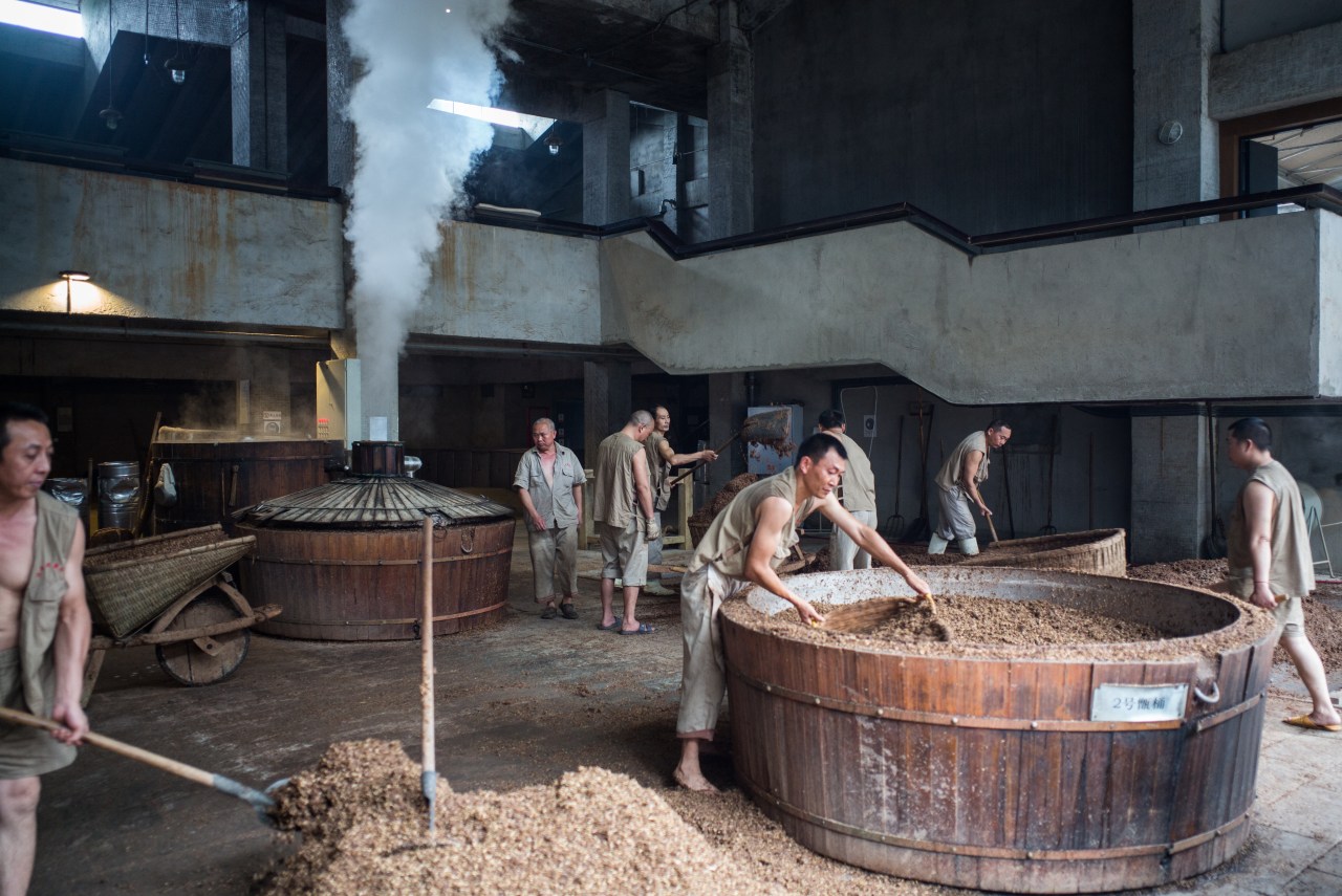 Workers fill vats with grain in preparation for alcohol production at the baijiu production demonstration area at the Shui Jing Fang Museum in Chengdu, China.