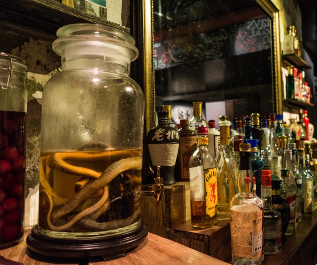 Photo 1: A snake flavored baijiu stands behind the bar at Capital Spirits. Photo 2: At a restaurant in Chengdu a worker prepares to down a shot of baijiu.