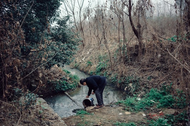 Photo 1: Mr. Li gathers water for his plot of greens and vegetables near his apartment in San Sheng Flower Town. Retired at 67, Li tends his plants during his spare time. Photo 2: Local residents return home from the market in Sansheng Flower Town.