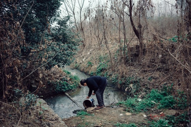 Photo 1:  Mr. Li gathers water for his plot of greens and vegetables near his apartment in San Sheng Flower Town. Retired at 67, Li tends his plants during his spare time. Photo 2: Local residents return home from the market in Sansheng Flower Town.