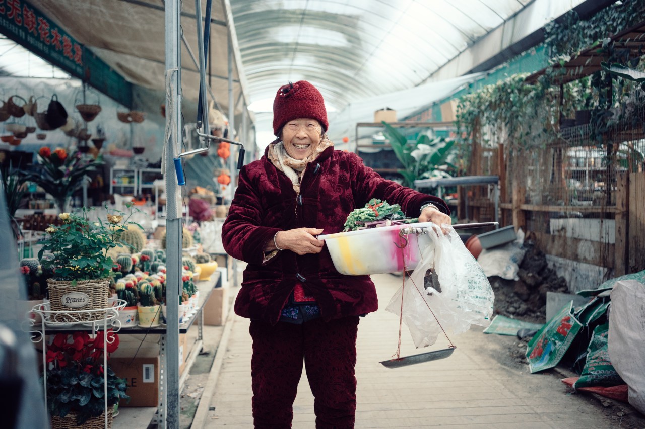 Mao, 79, sells her home grown vegetables in the flower market of San Sheng Flower Town.