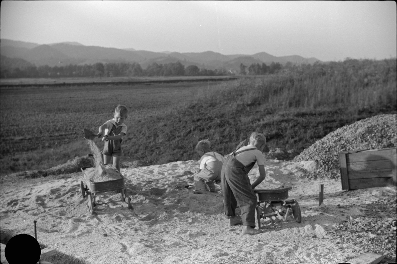Children play with sand in Tygart Valley, September 1938. The large black circle at the lower left of this frame was made by a hole punch, the preferred method of the photo editor to reject frames he did not wish to distribute. Photo by Marion Post Wolcott.