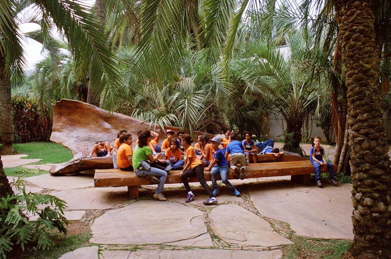 Local children from Inhotim’s school outreach program gather on one of the park’s trademark benches by Brazilian designer Hugo França.