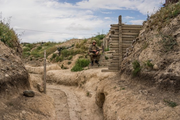 1. A soldier from the Nagorno-Karabakh armed forces at a front-line post near Talish. 2. A military jeep from the Nagorno-Karabakh armed forces approaches a base in Talish.