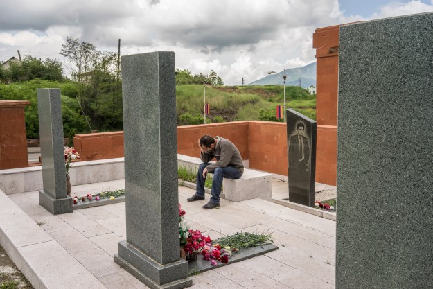 1. A man cries at the grave of a fighter killed in the 1990s war between Armenia and Azerbaijan. 2. Military officers wait for the start of the ceremony.