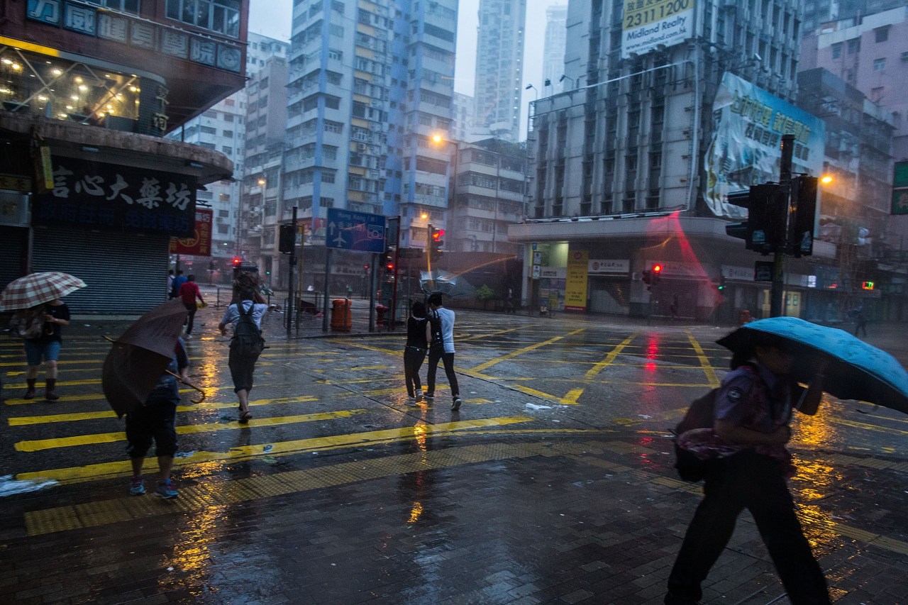 Pedestrians caught in high winds caused by a typhoon. Photo by Lam Yik Fei/Getty Images.