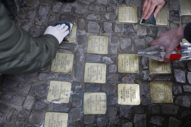 People clean the Stolpersteine memorials. Photo by Michele Tantussi via Getty Images.