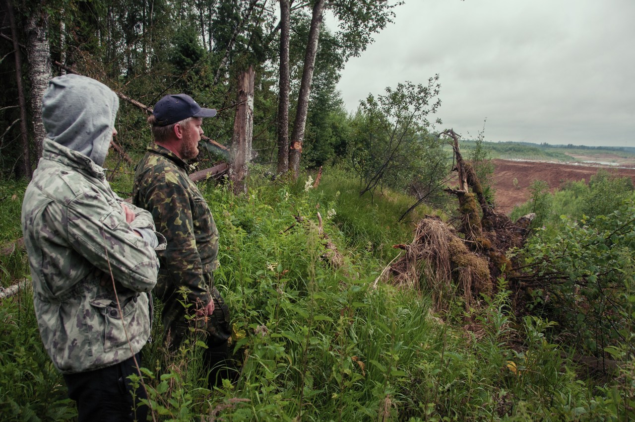 Kirill Artyukhov and a fellow activist stand at the edge of the forest overlooking the dumping site.
