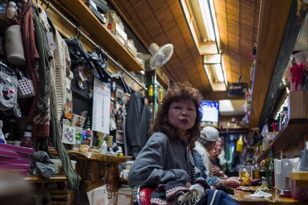 1. Patrons at an izakaya in the Tokyo suburb of Saitama. 2. Sake bottles line the bar at an izakaya in Tokyo.