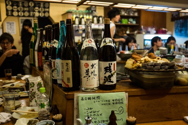 1. Patrons at an izakaya in the Tokyo suburb of Saitama. 2. Sake bottles line the bar at an izakaya in Tokyo.