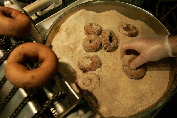 Cider doughnuts being dipped in sugar. Photo by Suzanne Kreiter / The Boston Globe via Getty Images.