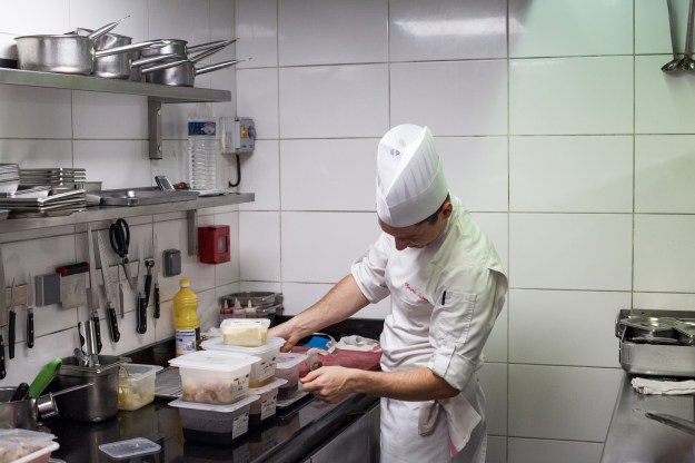1. A chef measures ingredients to prepare for a lunch service. 2. Chefs at work while the service is starting.