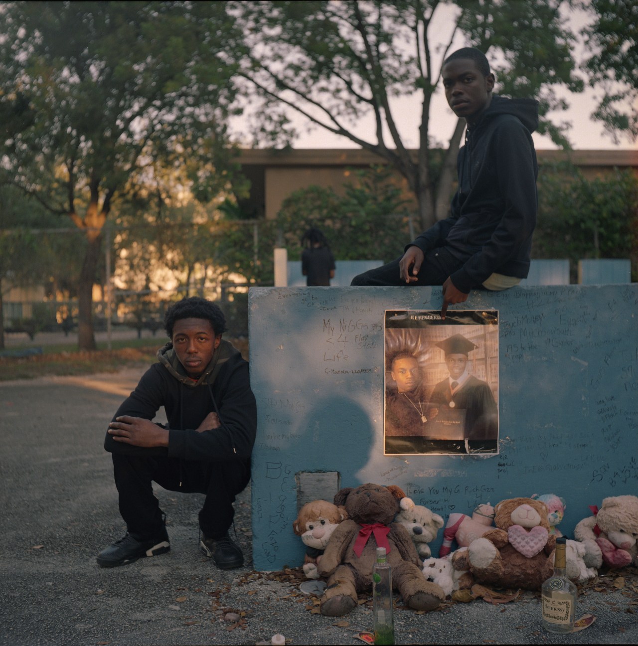 Two young men pose next to a memorial for their friend Jedadiah "Eggo" Scatliffe, who was shot and killed at 18.