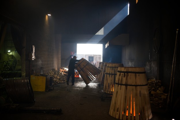 1: A cooper works on a cask. 2: Casks smoke after being toasted.