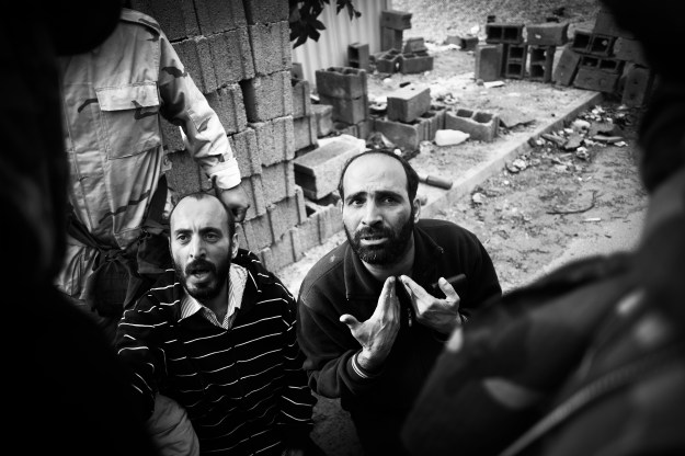 1: Libyan rebel fighters interrogate suspected Gaddafi loyalists captured while advancing into Sirte's downtown - October 2011. 2: A smoke column rises up from the Ouaga Dougou complex during the assault - October 2011.