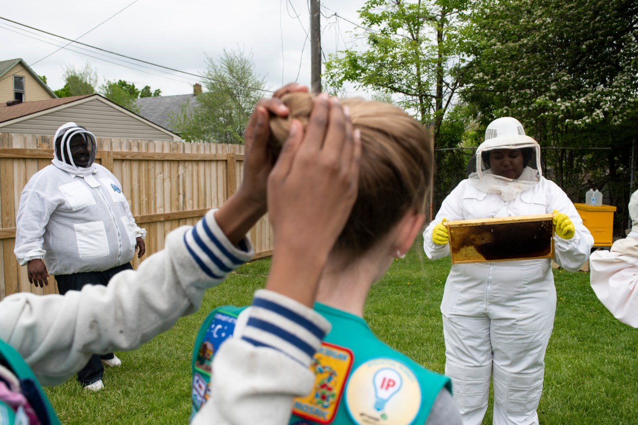 Lindsey displays a frame with bees during a hive inspection for Girl Scout Troop 40035 members.