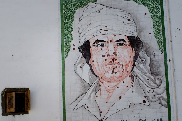 A mosaic of Gaddafi is seen on the wall of a building, riddled with bullett holes, on August 29, 2011 in Tripoli. Photo by Daniel Berehulak via Getty Images.