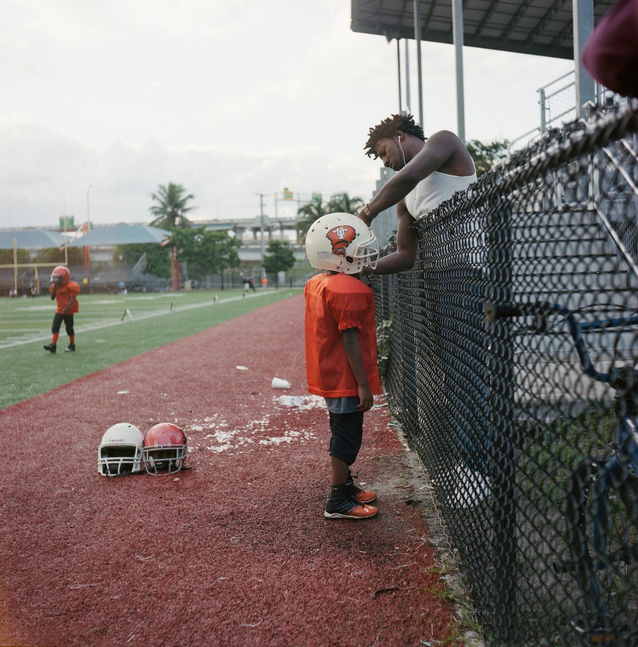 A father adjusts his son's helmet during an Overtown Tornadoes football practice.